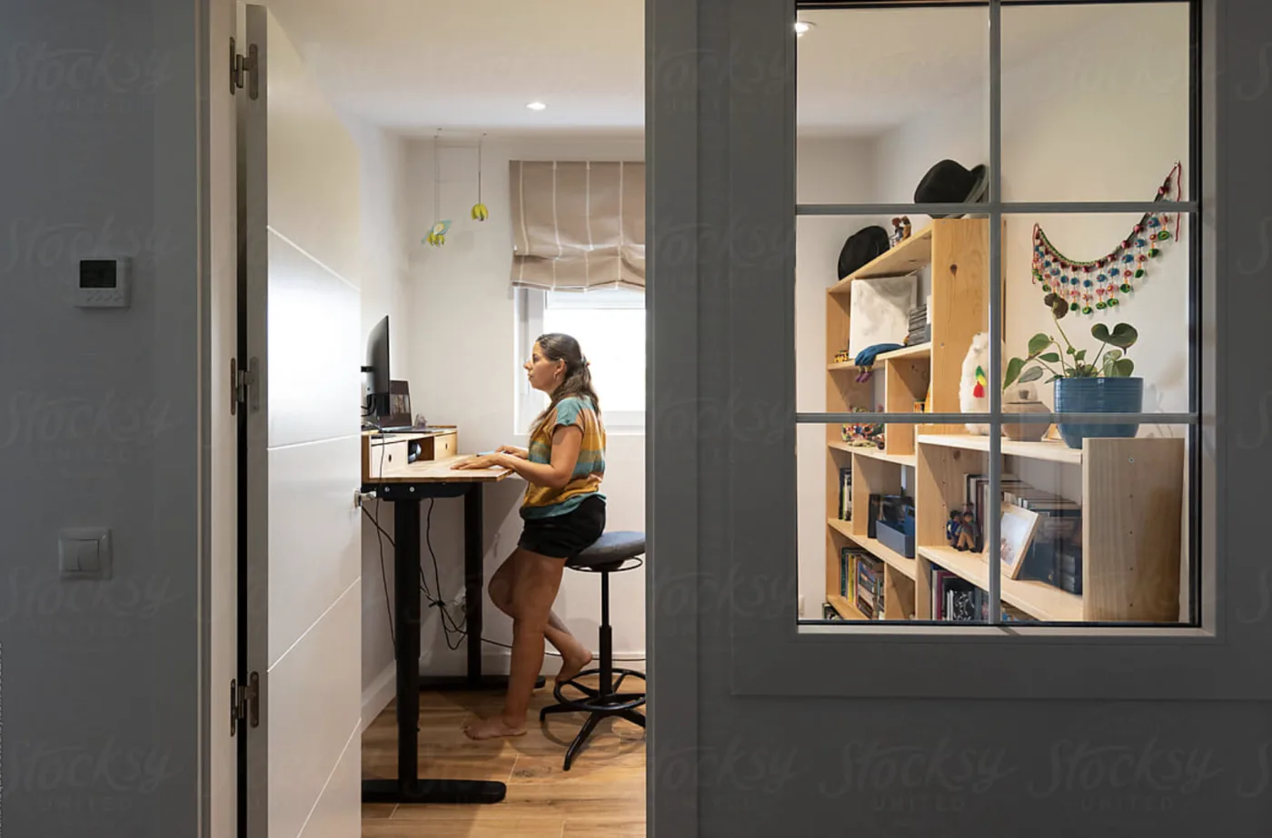 A coach smiling while working at her laptop in a bright home office